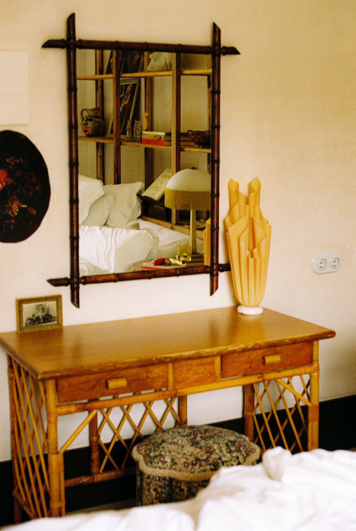 Bamboo-framed mirror over a rattan writing desk with vase