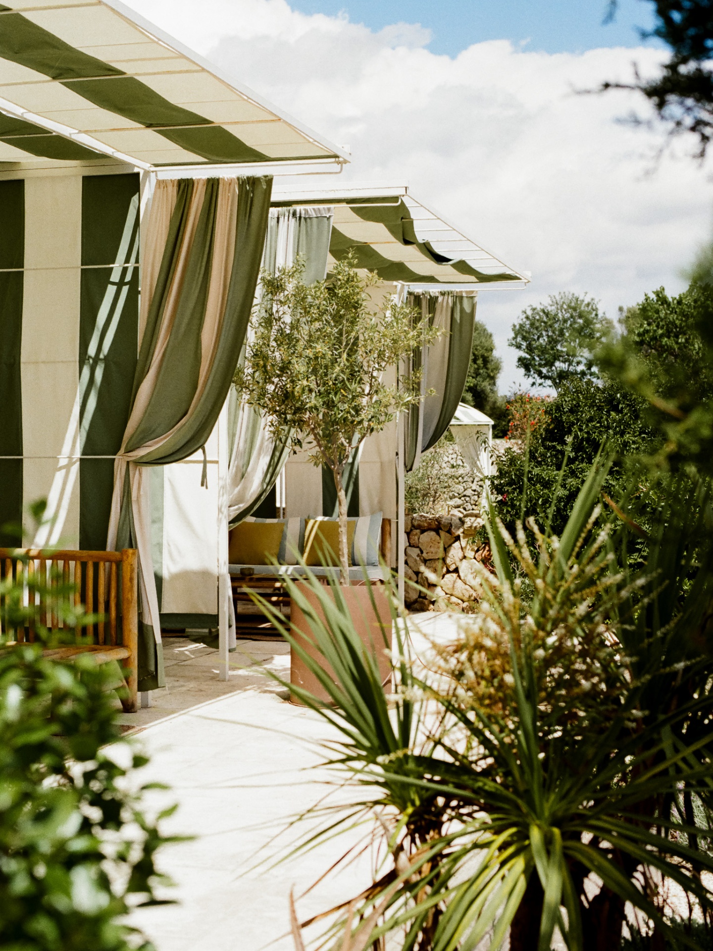 Green striped cabanas opening to a Menorcan garden