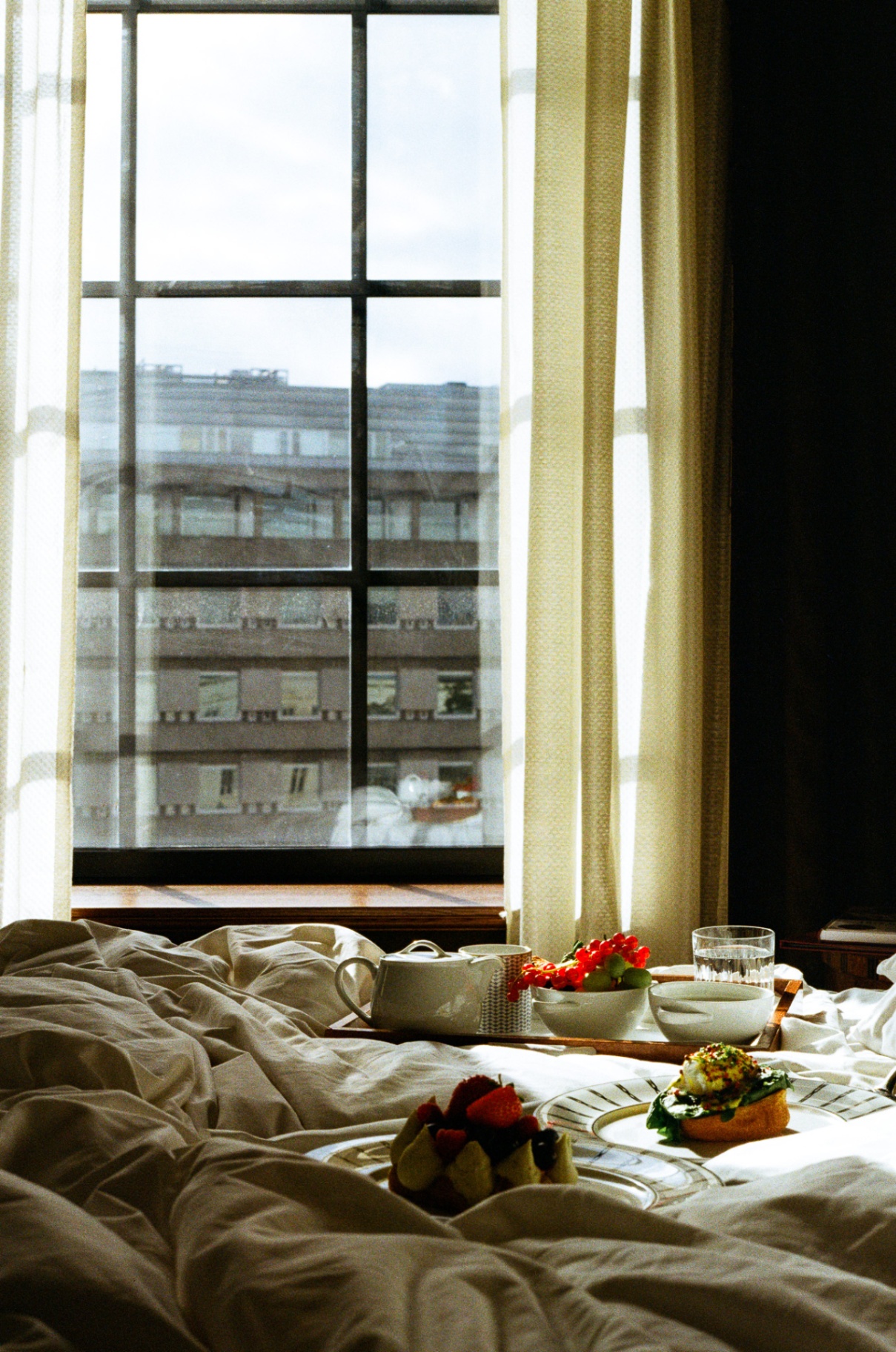Morning light through a tall window over an Oslo breakfast in bed