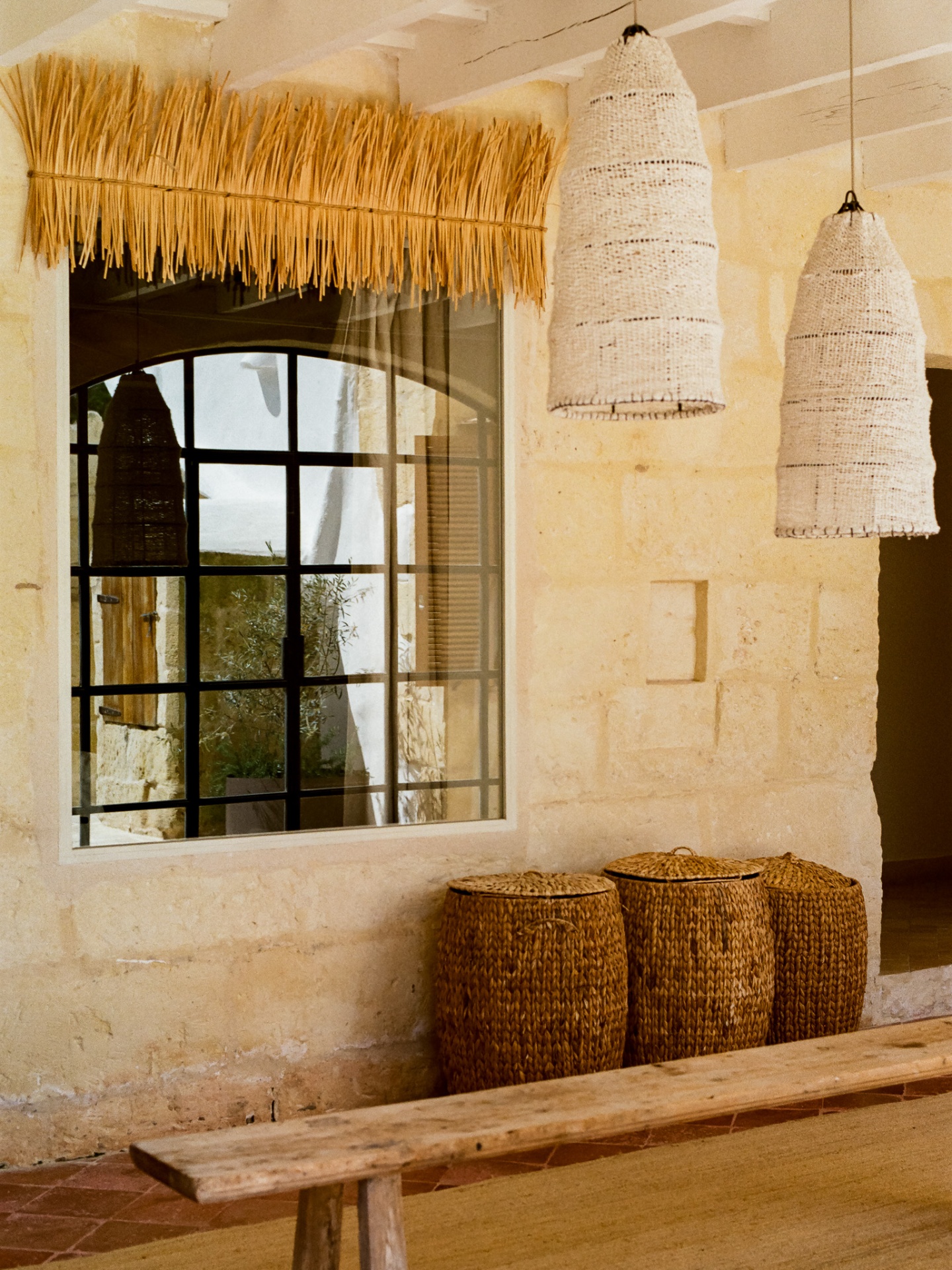 Arched stone window with woven pendant lamps and baskets