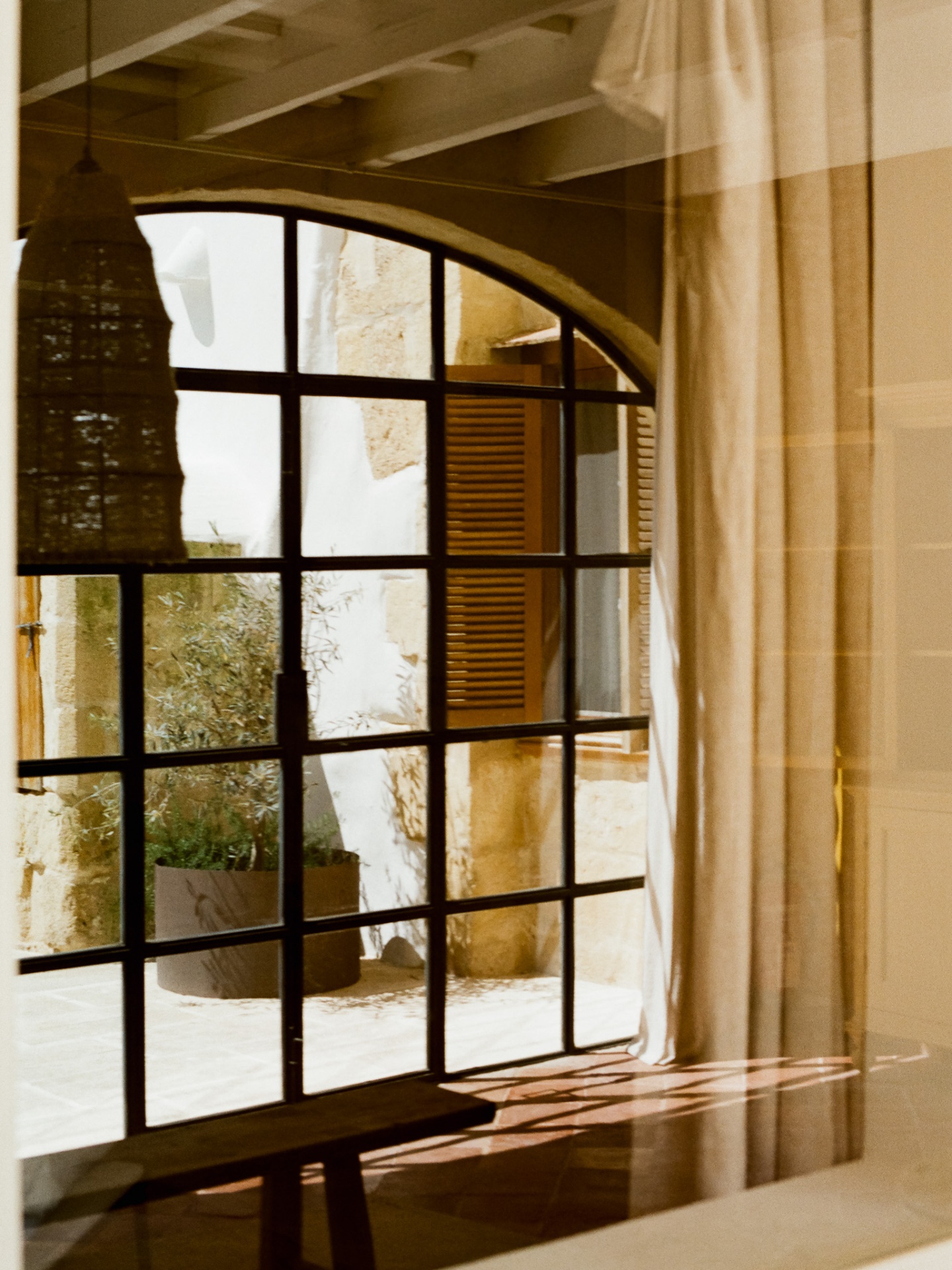 Reflection through an arched window into a Menorcan courtyard