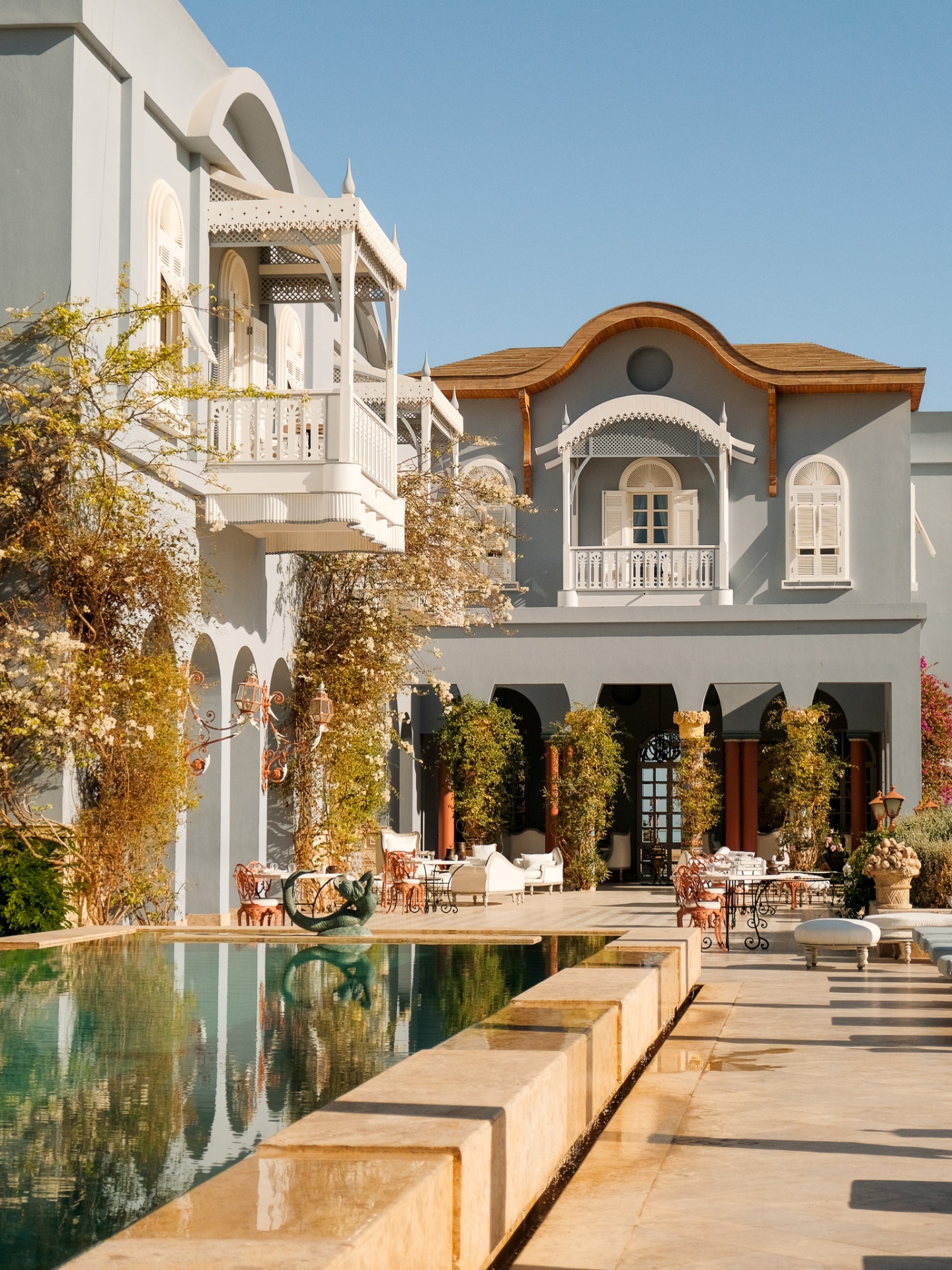 Pool reflecting the pale blue Maison Bleue facade at golden hour