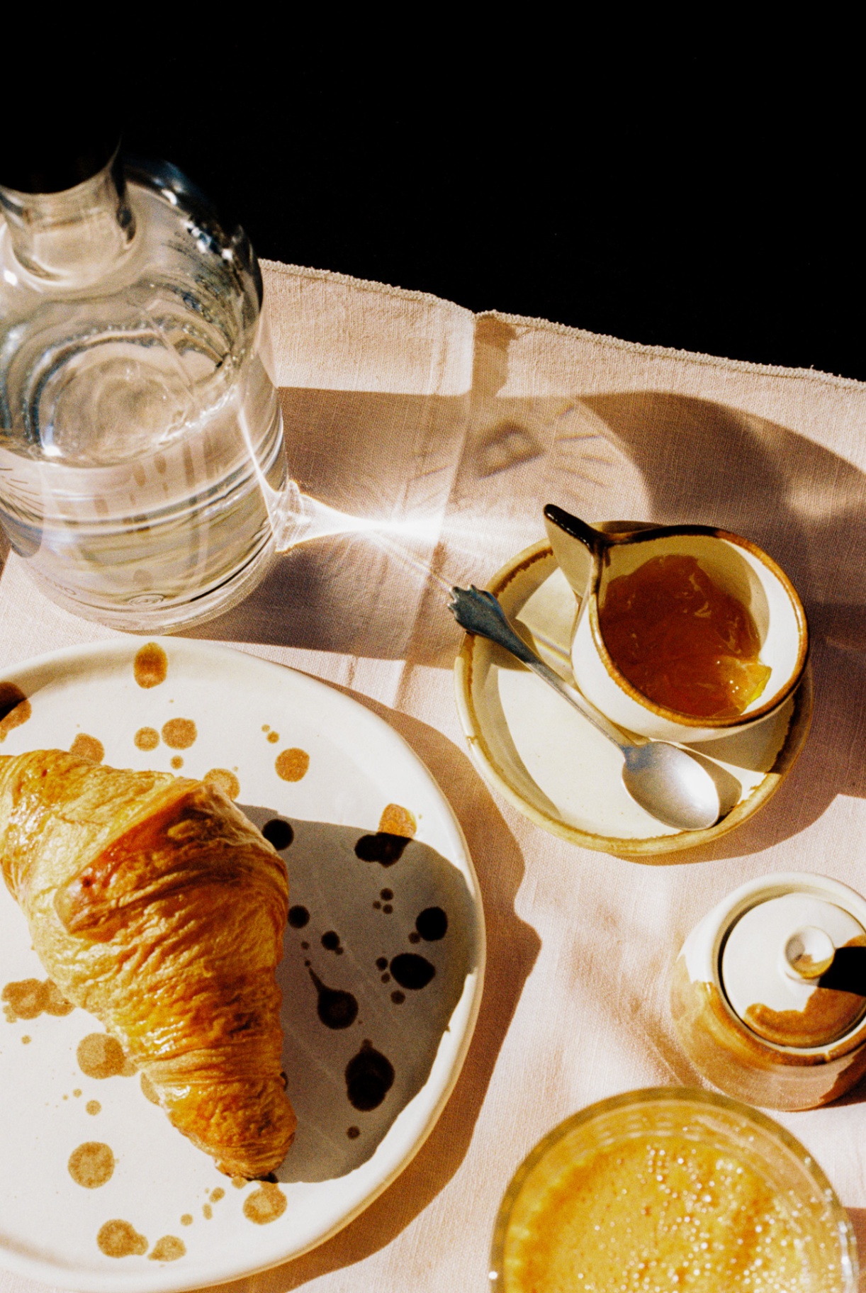 Croissant, marmalade and morning light on a linen breakfast cloth