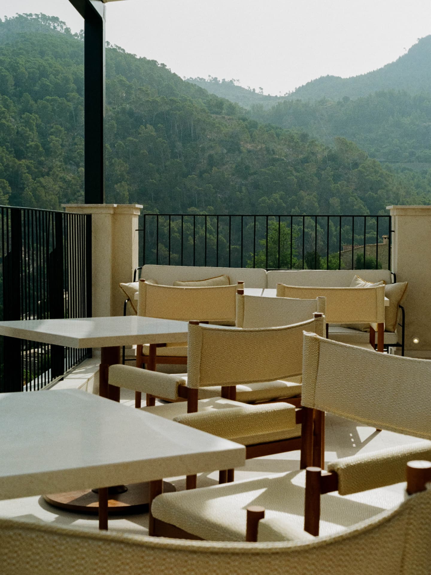 Terrace lounge chairs and stone tables framed by pine hills
