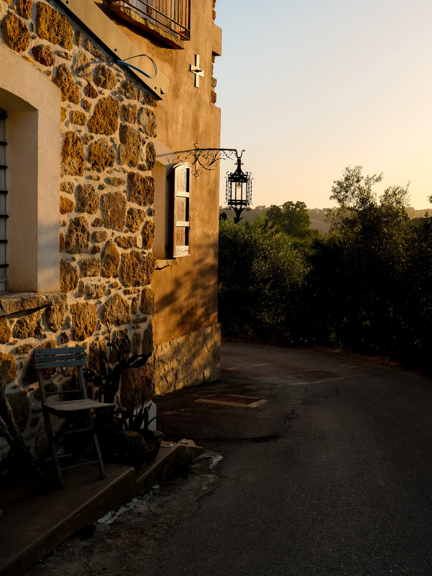 Stone cottage facade catching golden hour light with wrought-iron lantern