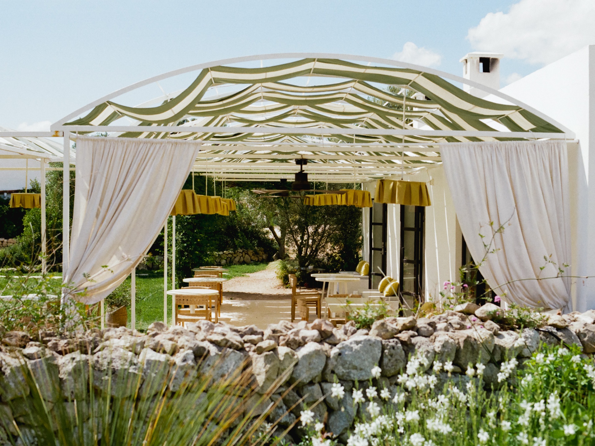 Pergola dining pavilion with billowing linen drapes