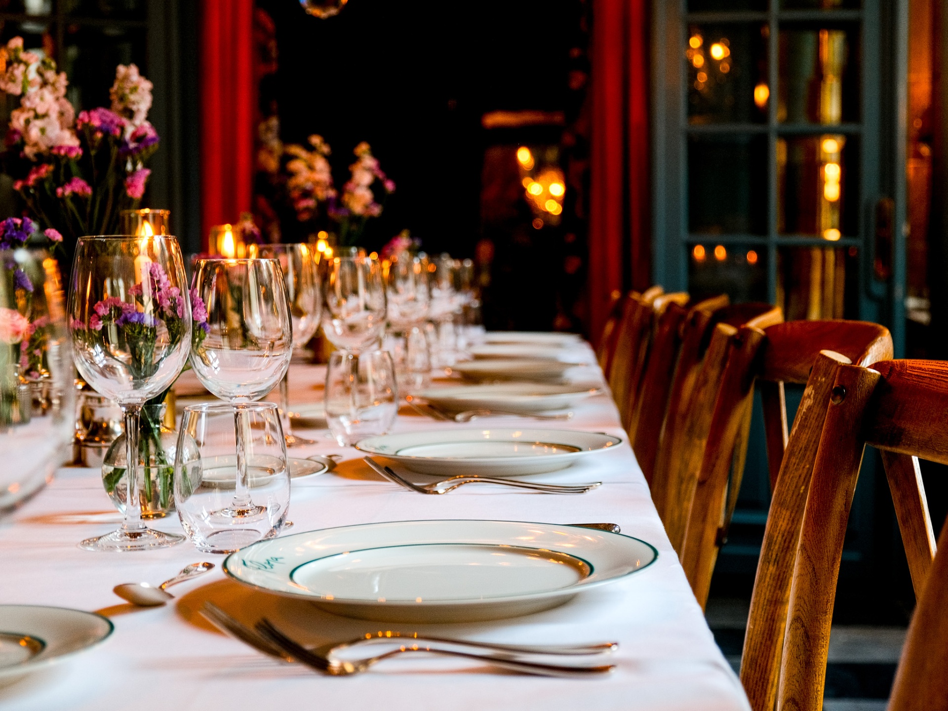 Long candlelit dinner table set with crystal and wildflowers