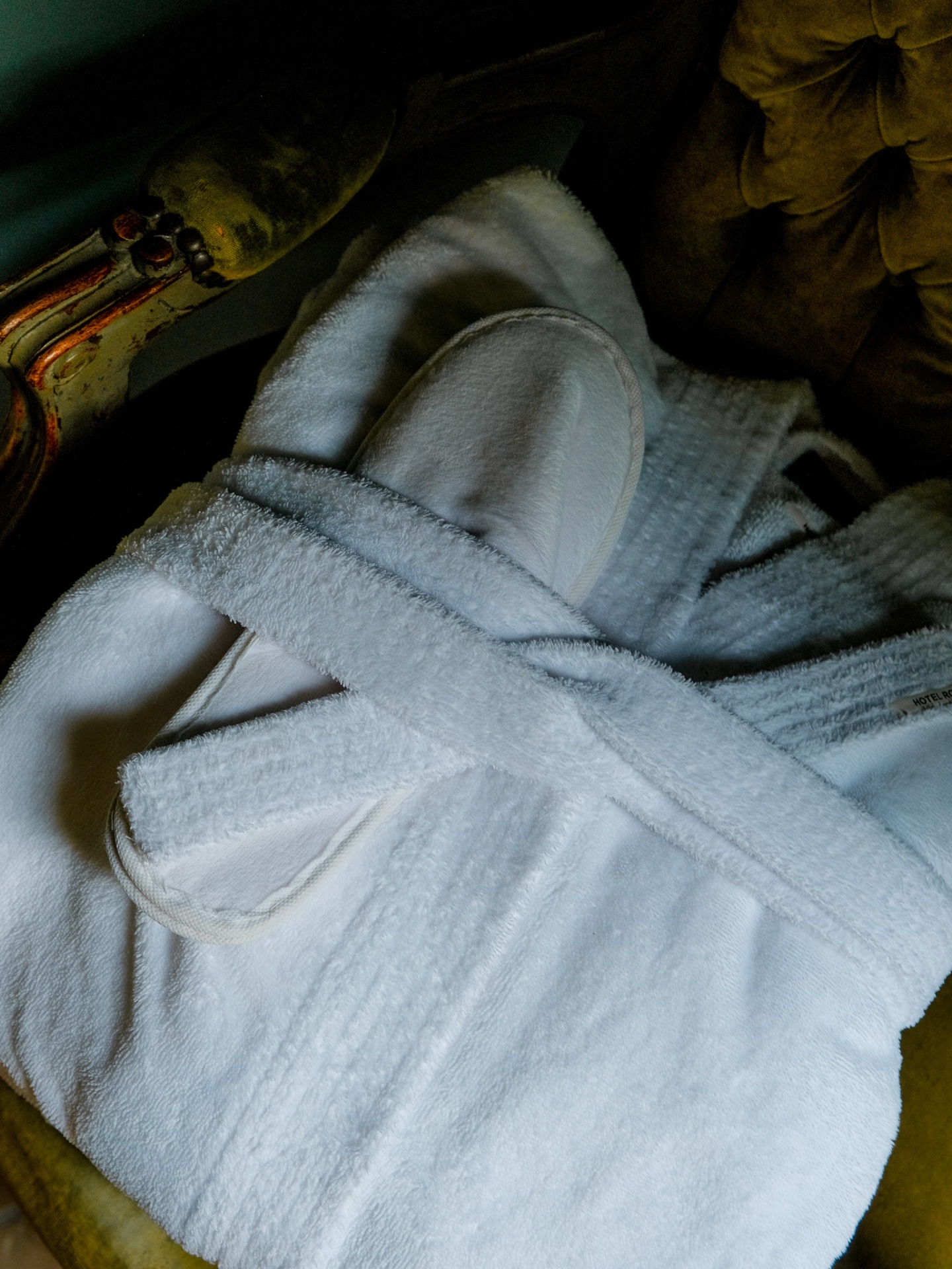 White bathrobe and slippers on a velvet chair