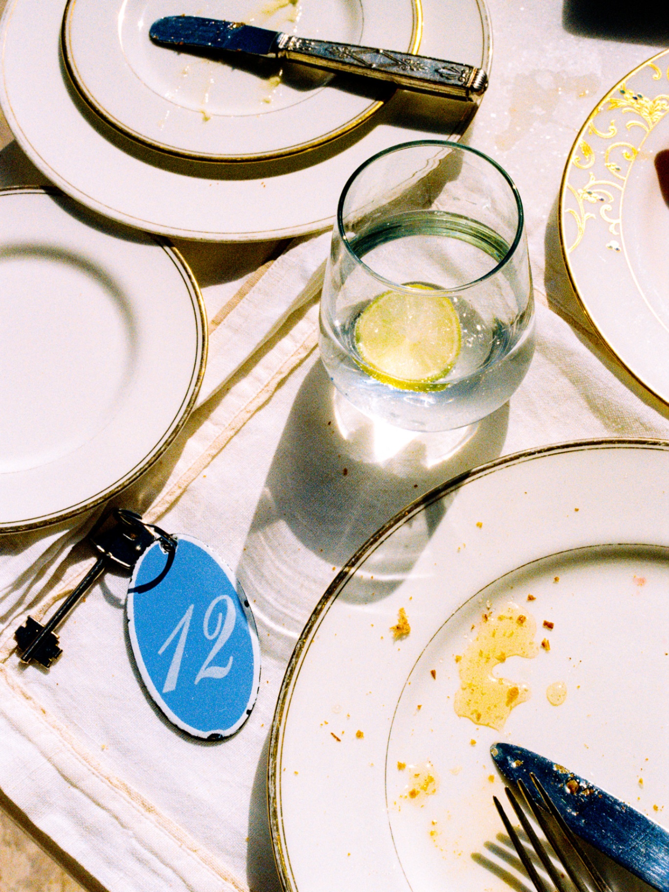 Room key '12' beside used plates and a glass of lime water