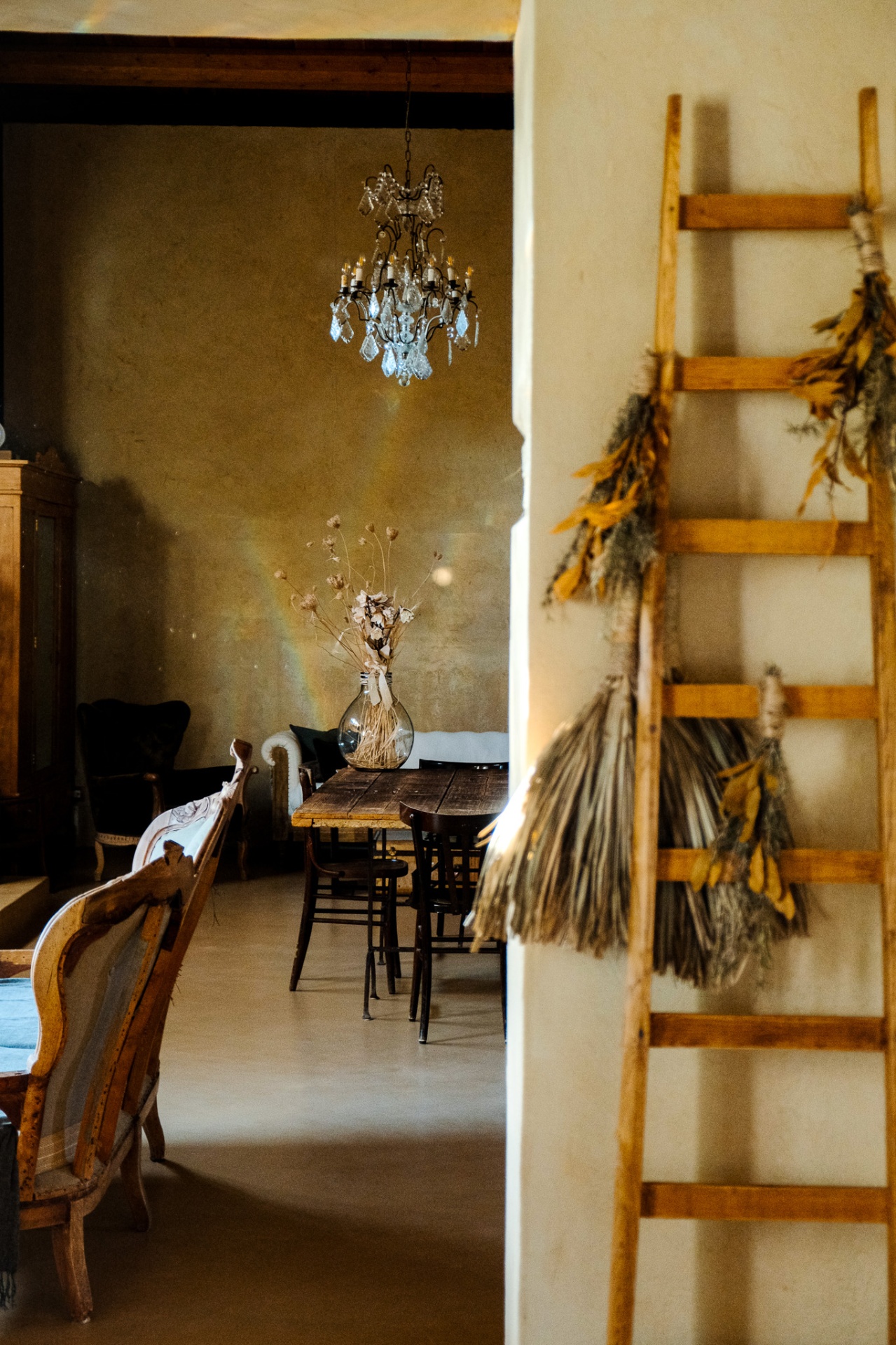 Crystal chandelier above a rustic dining table seen through a doorway