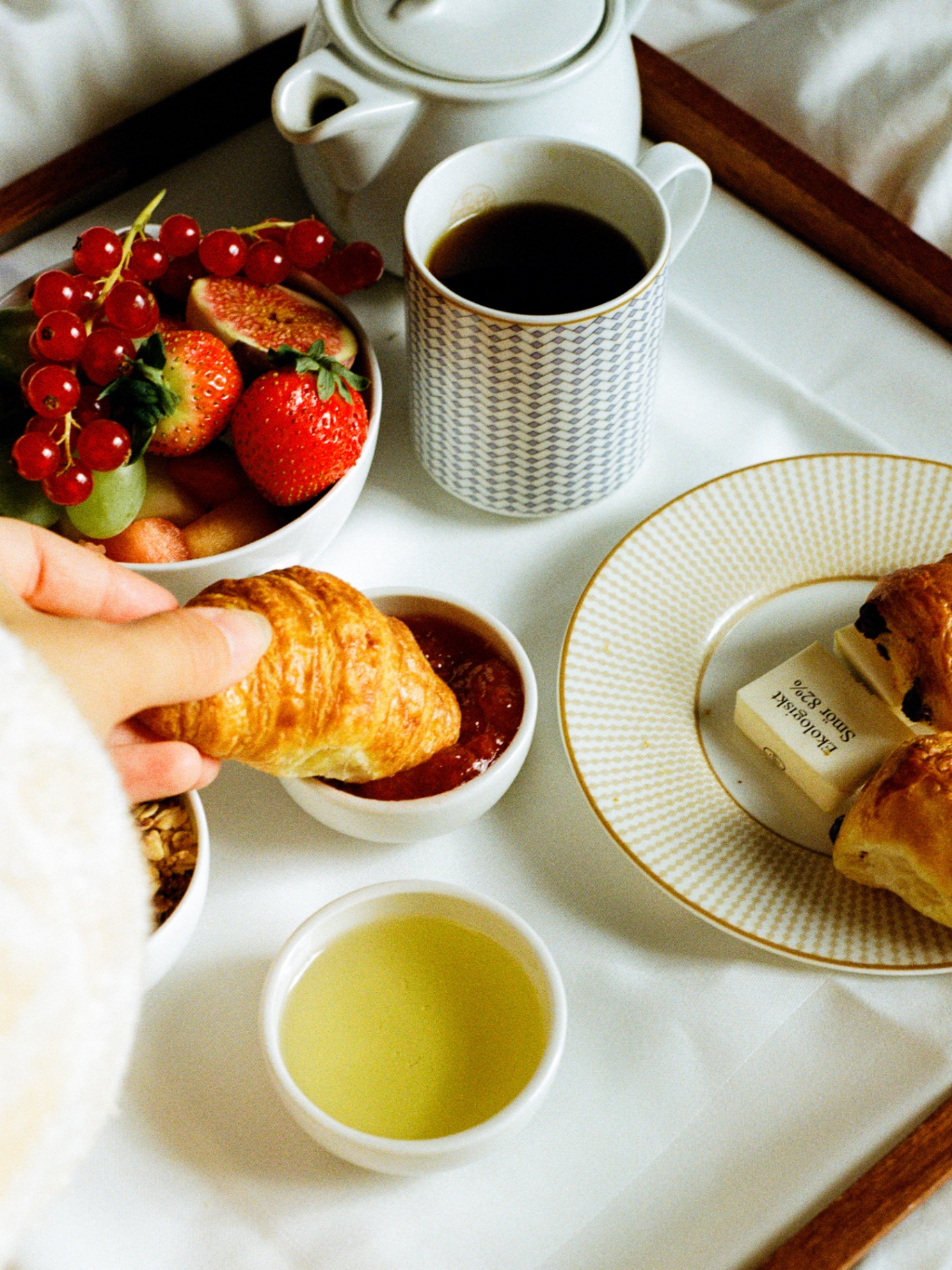 Hand dipping a croissant into strawberry jam on a Sommerro tray